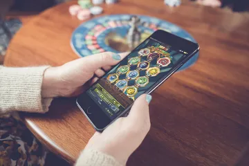 A man focused on his laptop with live stats in the background, highlighting the dedicated sports and gaming features of the 7555BET mobile app.
