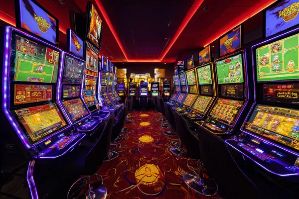7555BET Slots — Thousands of thrilling machines await A woman smiling by bright slot machines showing lucky symbols, showcasing the exciting slot offerings at 7555BET.